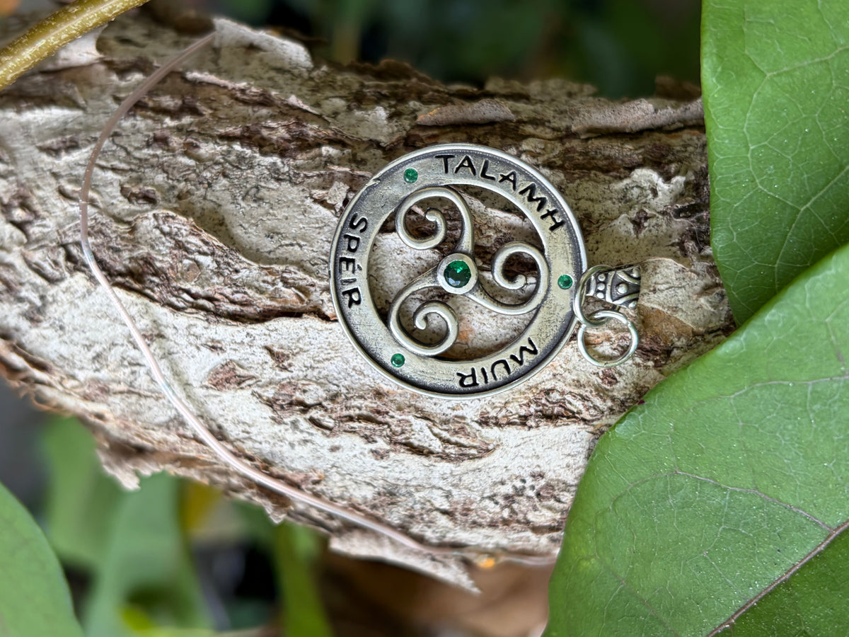 Celtic triskelion charm with Talamh Muir Speir inscription and green stones