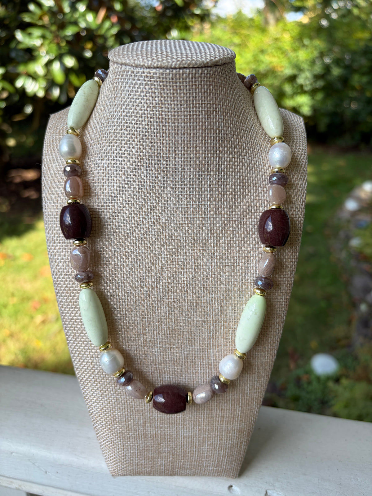 Close-up of mixed stone necklace beads draped over leaves
