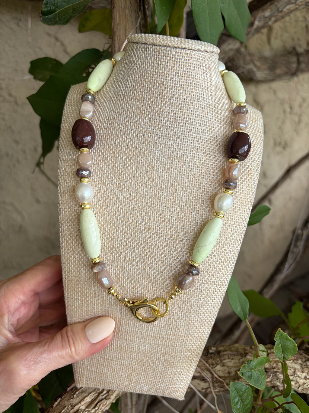 Mixed stone necklace on bust against stone wall