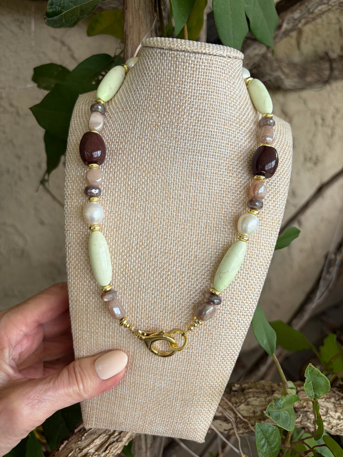 Mixed stone necklace on bust against stone wall