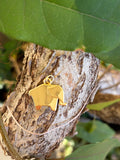 Gold origami elephant charm with jump ring bail on tree bark