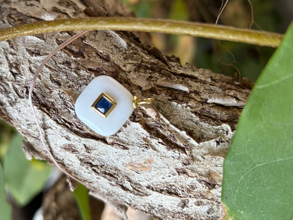 White enamel cushion square charm with navy blue center stone on tree bark