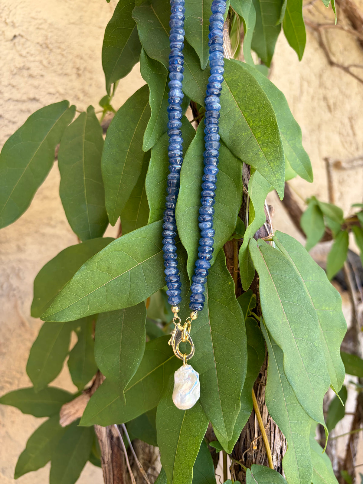 Kyanite heishi necklace with baroque pearl pendant on branch close up