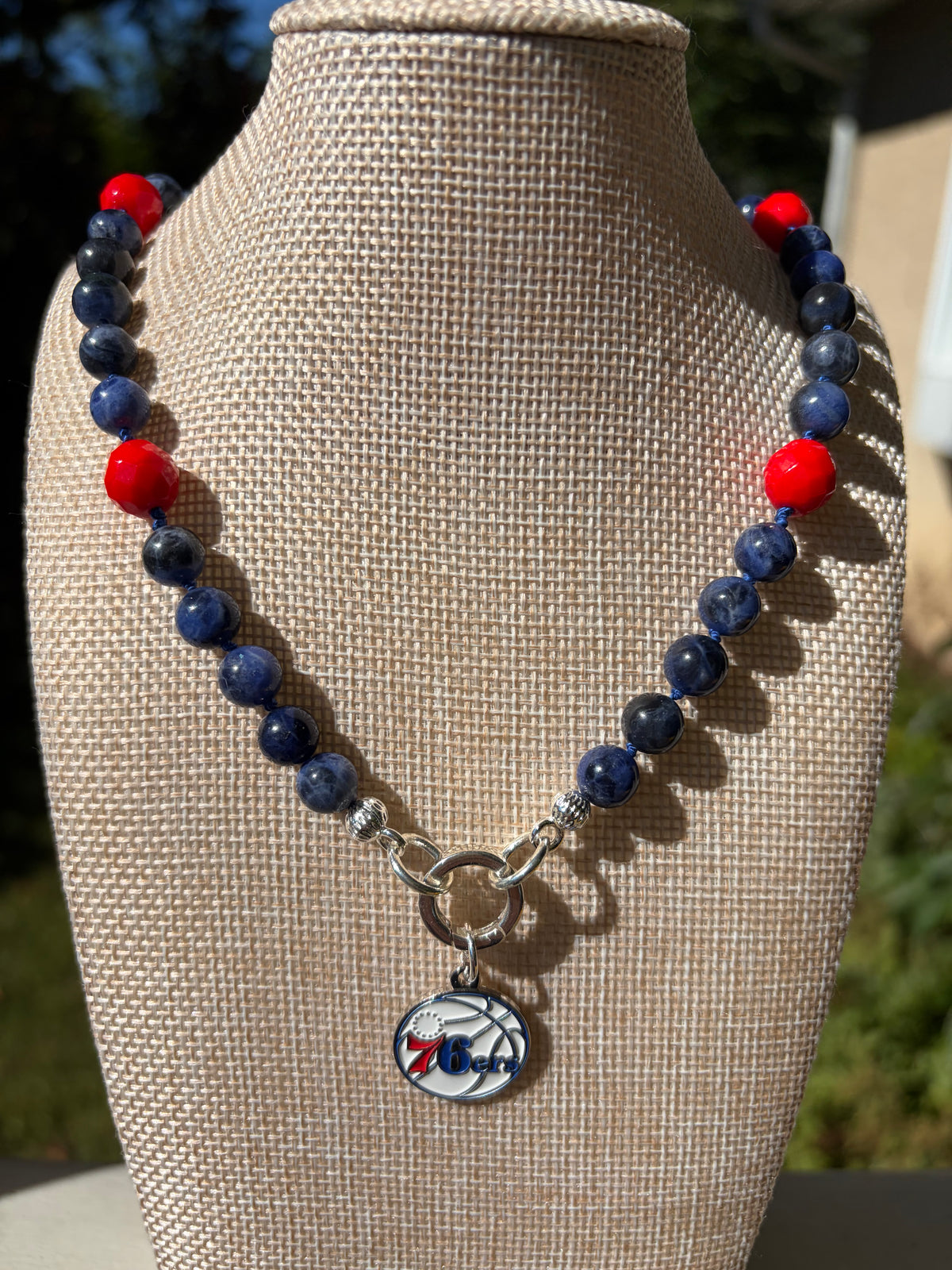 Sodalite and coral necklace with 76ers charm on mannequin bust in sunlight