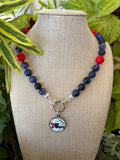 Sodalite and coral necklace with 76ers charm on mannequin bust with colorful foliage
