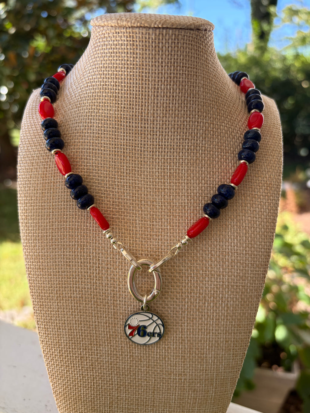 Lapis and red rice bead 76ers necklace with gold toggle clasp on mannequin bust outdoor