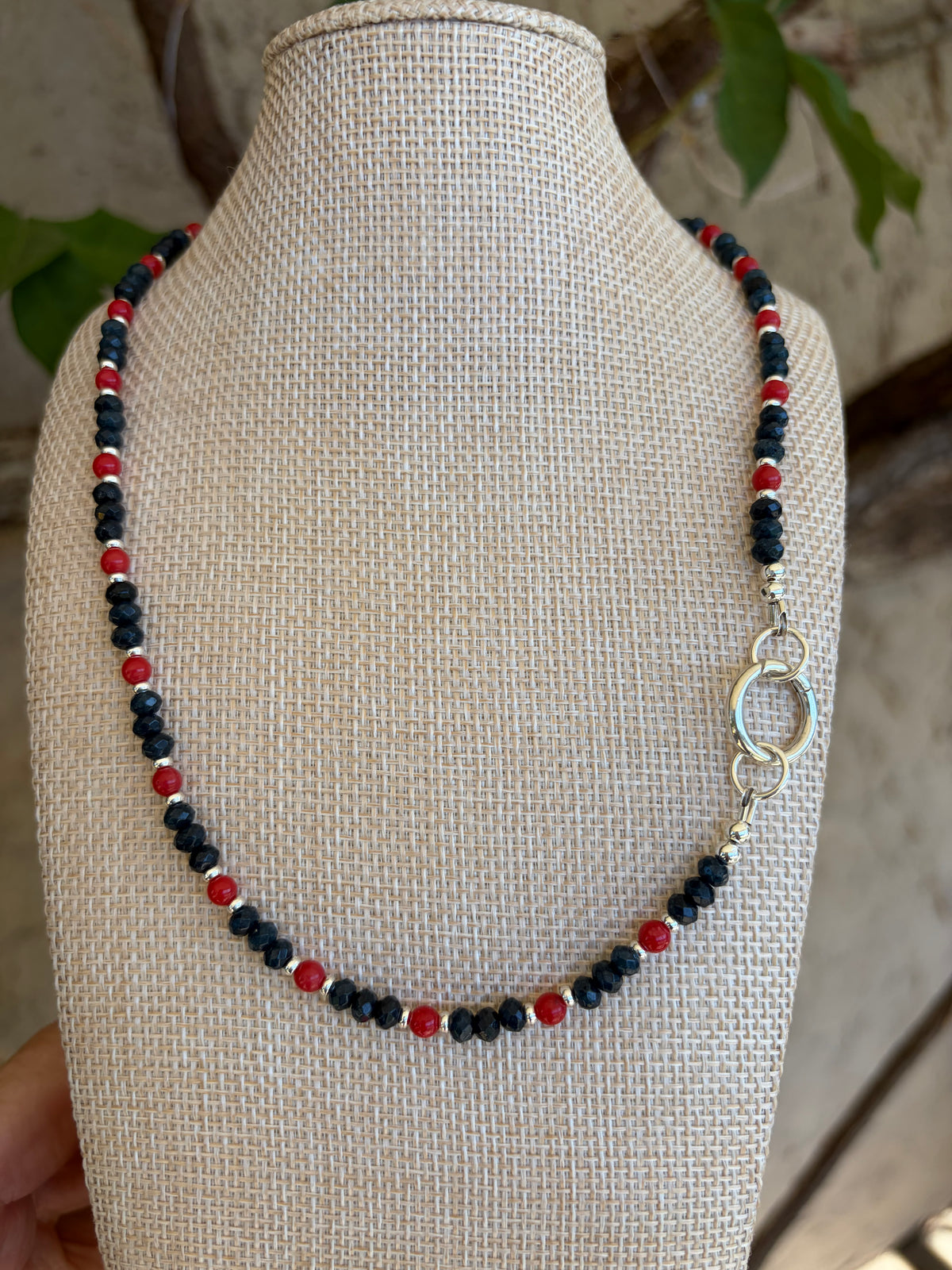 Navy crystal and red bead necklace on mannequin bust in garden