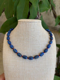 Lapis lazuli beaded necklace with gold toggle clasp on green leaves